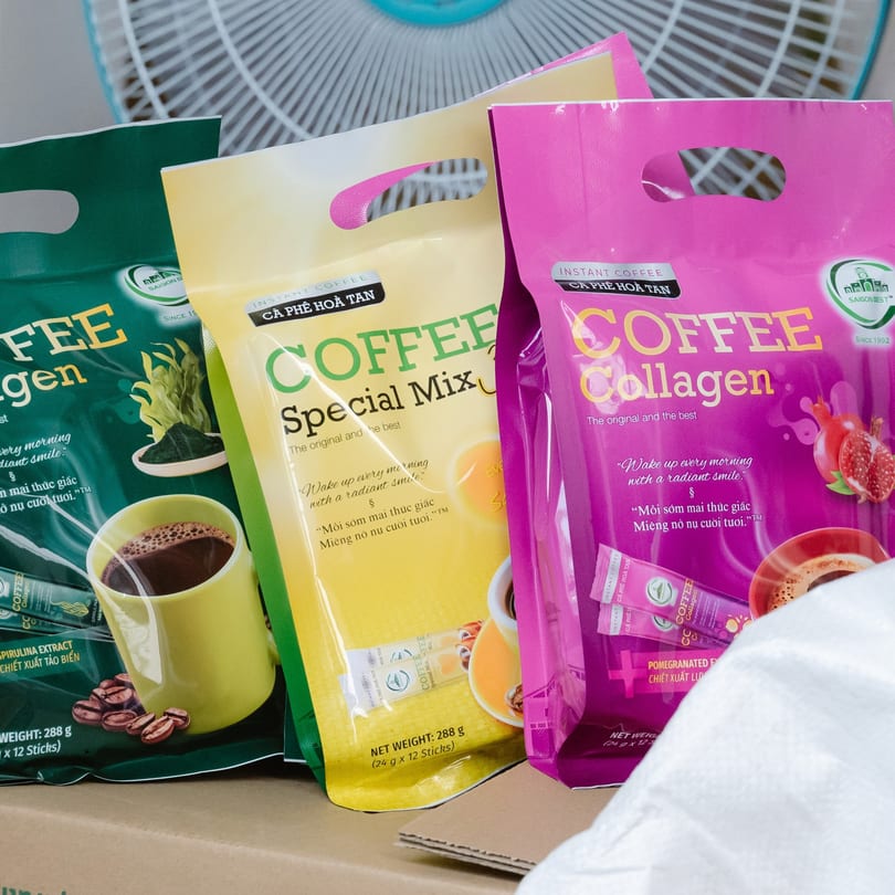 Three colorful bags of Cafe LaVie Vietnamese instant coffee, including Collagen and Special Mix varieties.