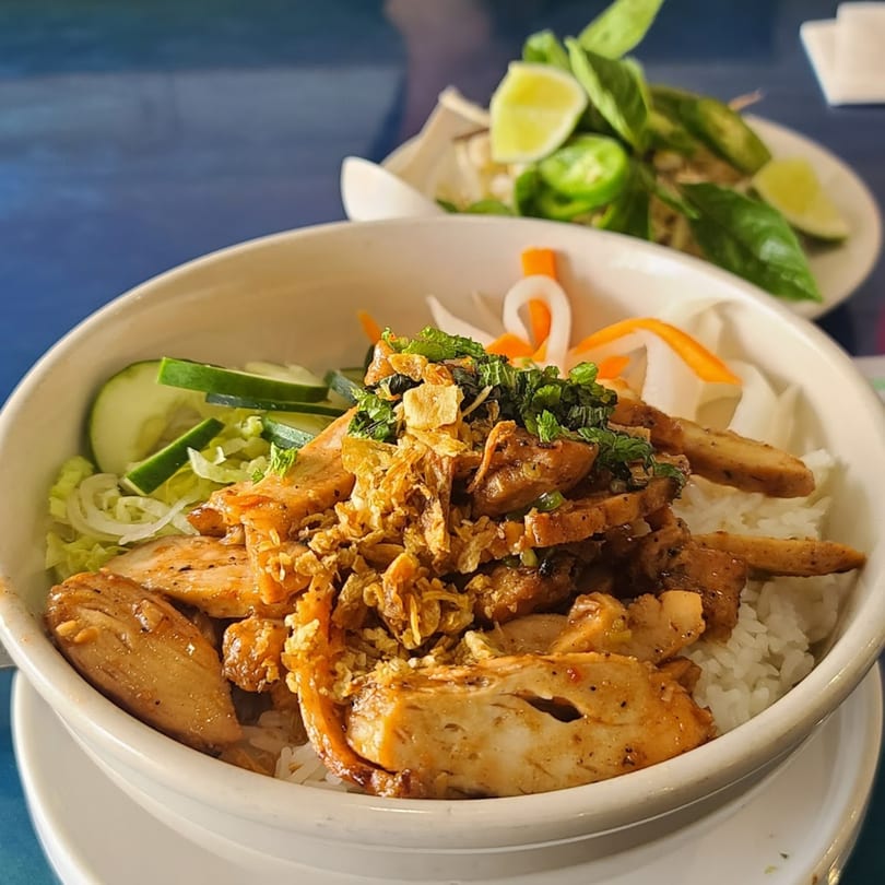 Cafe LaVie's grilled chicken rice bowl with fresh vegetables and a side of herbs and lime.